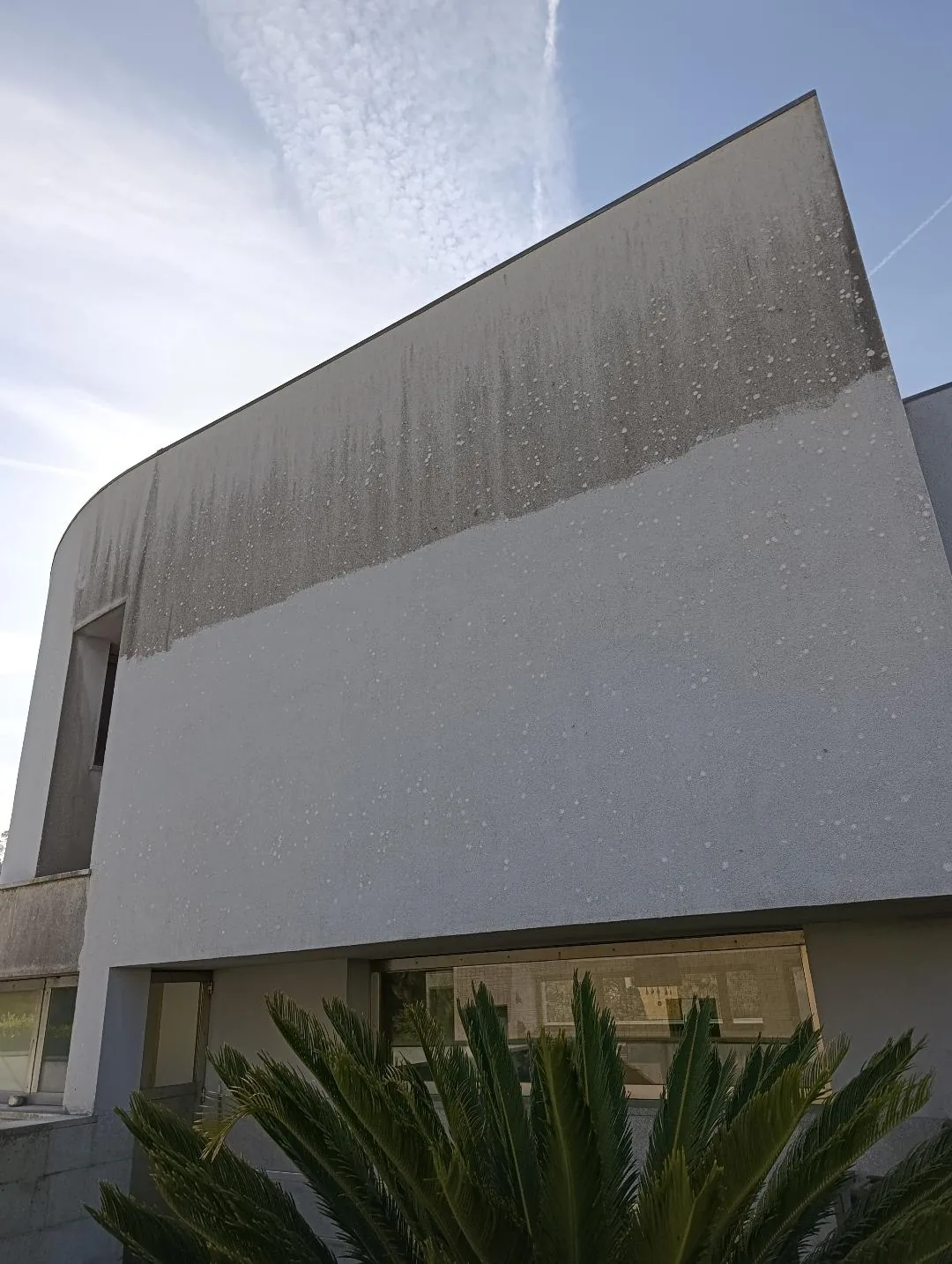 Antes e depois da lavagem de capoto de uma fachada — parte superior suja e parte inferior limpa