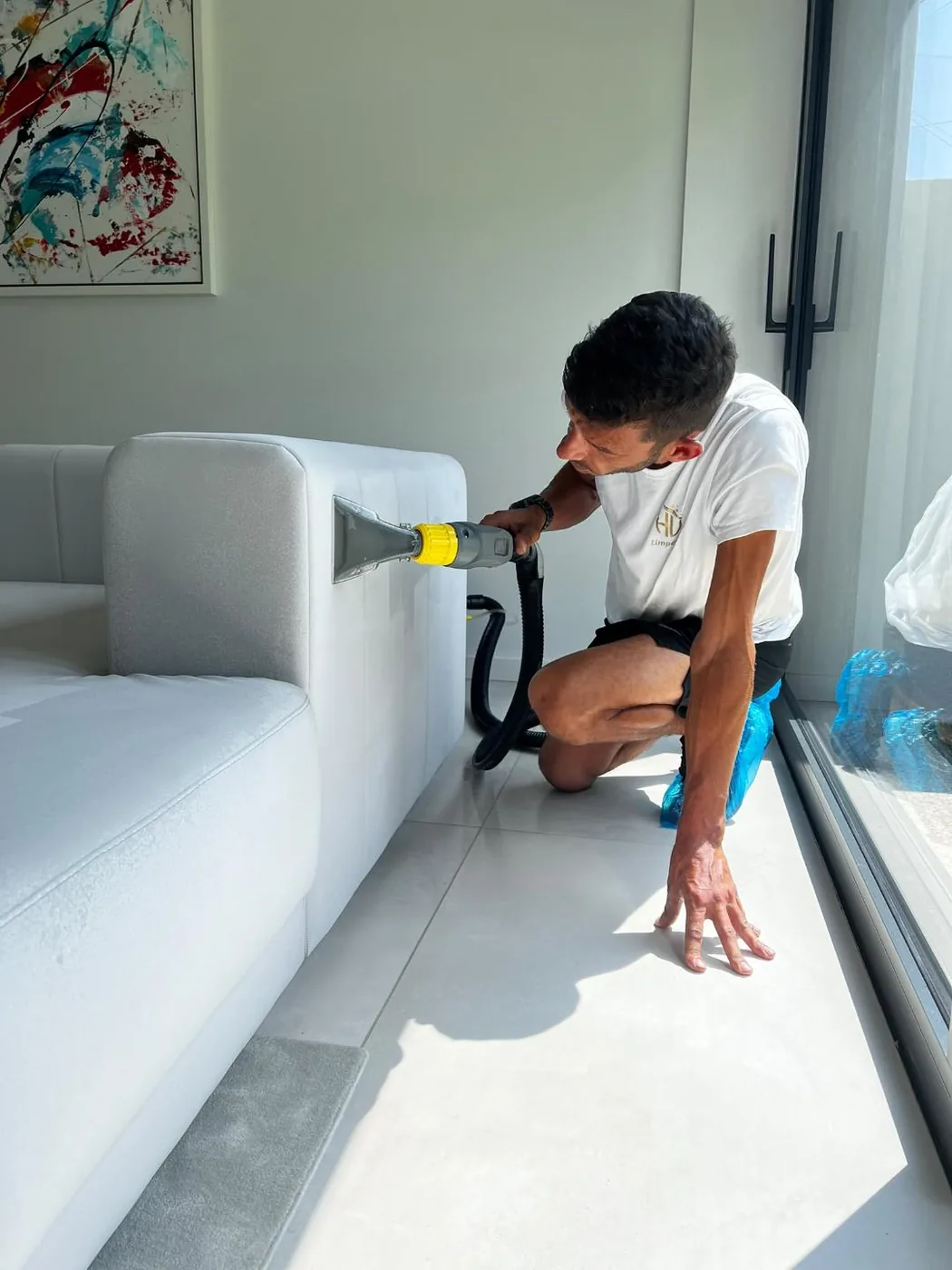 Higienização de um sofá com máquina de injeção-extração, por colaborador da HV Limpezas