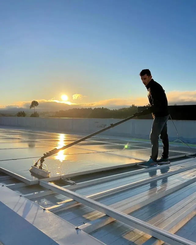 Limpeza de painéis solares ao nascer do sol com vara de água purificada